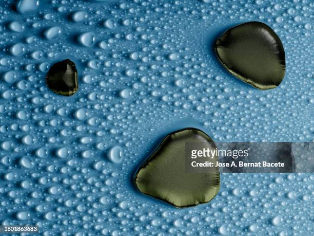 large drops of green liquid on a blue wet surface with small water droplets. - couronne d'eau photos et images de collection