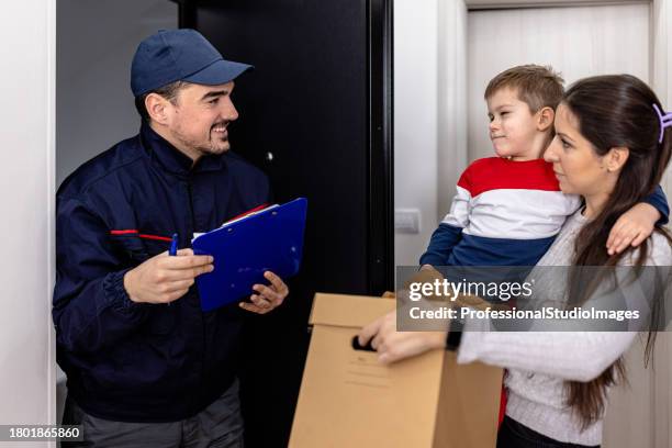 a delivery man is standing on a doorstep and giving a paper box to a young woman with a little kid. - freedom of expression is a right and not granted stock pictures, royalty-free photos & images