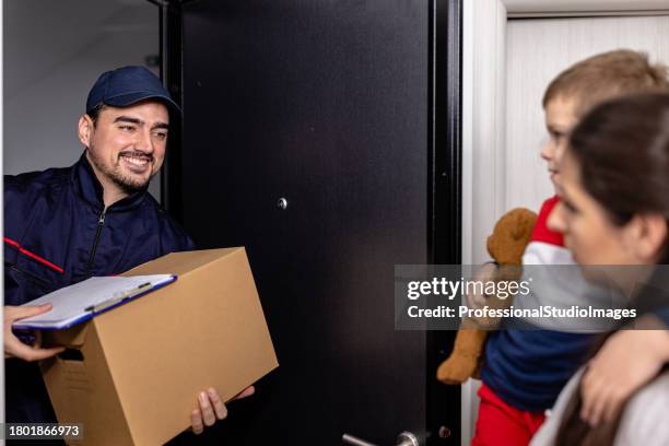 a young delivery guy is bringing a paper box to a young woman with her son at the doors. - freedom of expression is a right and not granted stock pictures, royalty-free photos & images