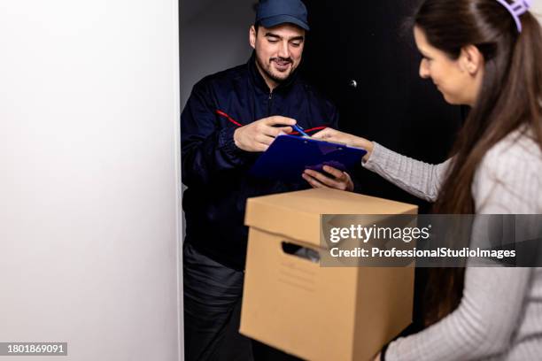 a young delivery guy is bringing a paper box to a young woman at the doors. - freedom of expression is a right and not granted stock pictures, royalty-free photos & images