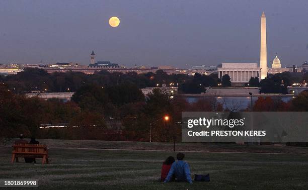 The full moon rises over the Washington, DC, area as couples view the skyline from the grounds of the Iwo Jima Memorial in Arlington, Virginia, 31...