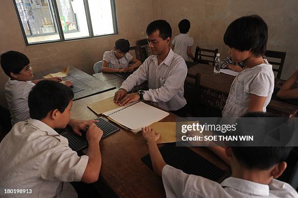 This photo taken on September 9, 2013 shows blind and visually-impaired students learning to write the Braille alphabet at the Yangon Education...