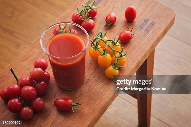 a glass of tomato juice and newly picked tomatoes - tomatensap stockfoto's en -beelden