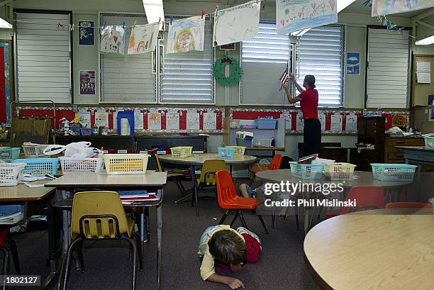 Kindergarten teacher closes the windows as her students crawl under their desks during a classroom lockdown drill February 18, 2003 in Oahu, Hawaii....