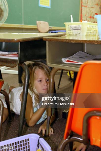 Kindergarten student hides under her desk during a classroom lockdown drill February 18, 2003 in Oahu, Hawaii. Lockdown procedure is used to protect...