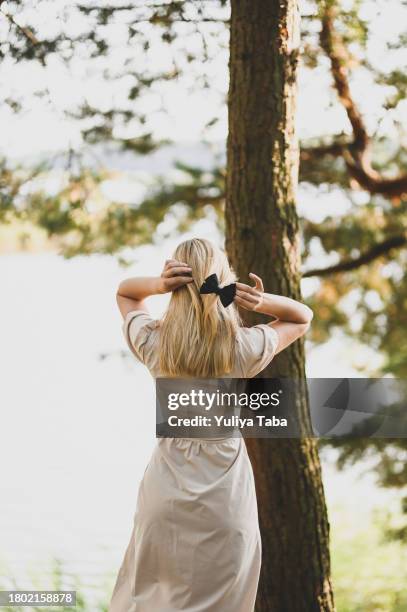 rückansicht einer blondhaarigen frau in einem wald. - hair accessory stock-fotos und bilder