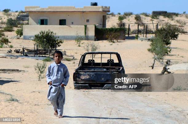 An Egyptian child walks in front of the wreckage of a burnt down car, the day after an attack by Egyptian Army in a village on the outskirt of the...