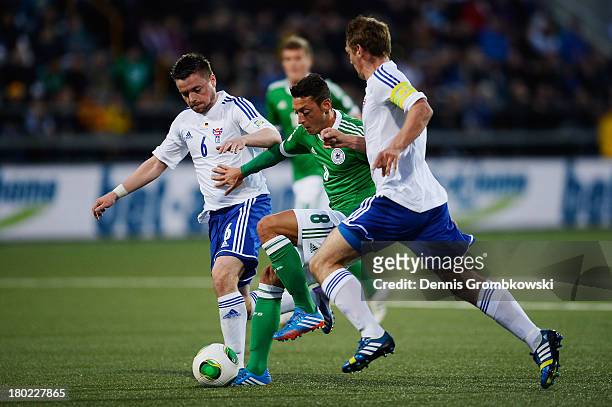 Mesut Oezil of Germany is challenged by Suni Olsen of Faeroe Islands during the FIFA 2014 World Cup Qualifier match between Faeroe Islands and...