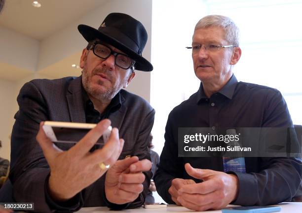 Musician Elvis Costello and Apple CEO Tim Cook look at the new iPhone 5S during an Apple product announcement at the Apple campus on September 10,...