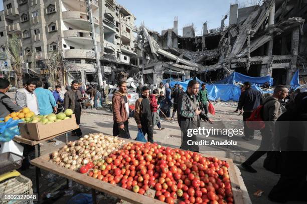 Palestinians do shopping to fulfill their essential needs during the second day of the humanitarian pause amidst destroyed buildings due to Israeli...