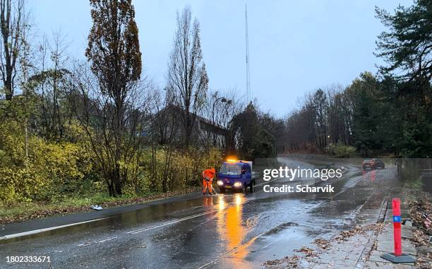 person attempting to unclog sidewalk drain during flood - storm drain stock pictures, royalty-free photos & images