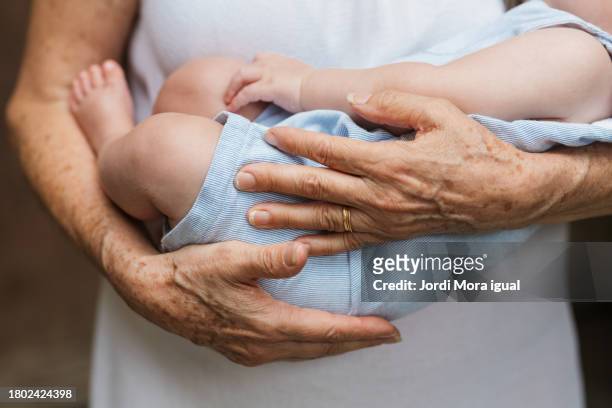 close-up of baby boy sleeping in arms of a person - grandma sleeping stockfoto's en -beelden