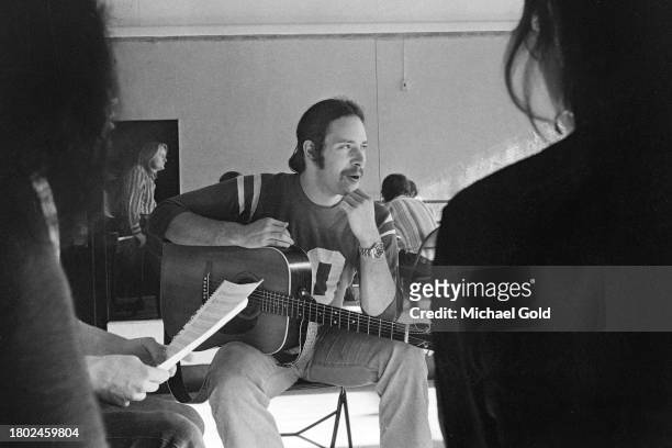 'Lemmings' actor Christopher Guest playing his guitar with Director Tony Hendra in the background during rehearsal in a rehearsal hall in New York...