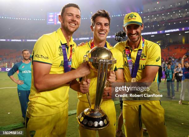 Josh Hazlewood, Pat Cummins and Mitchell Starc of Australia poses with the ICC Men's Cricket World Cup Trophy following the ICC Men's Cricket World...