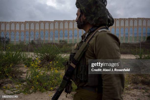An IDF officer walks past the protective barriers near the border fence with the Gaza Strip part of the this community on November 19, 2023 in Netiv...