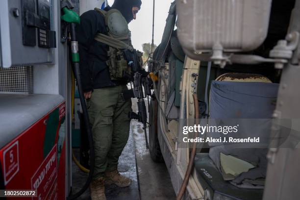 An IDF soldier fills a hummer with petrol at a petrol station near the Gaza border on November 19, 2023 in Southern Israel. More than a month after...