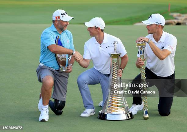 Nicolai Hojgaard of Denmark holds the DP World Tour Championship trophy whilst Rory McIlroy of Northern Ireland who won the DP World Tour Race to...