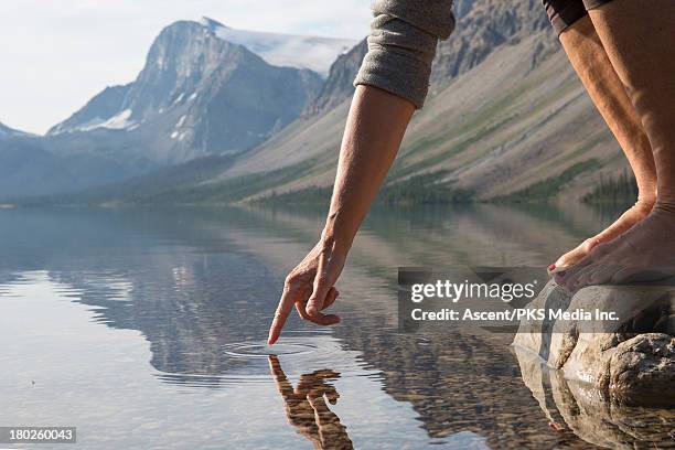 woman's hand touches water surface, mtn lake - physical senses stock pictures, royalty-free photos & images