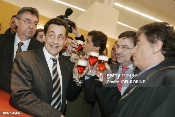 Former French Finance Minister Nicolas Sarkozy and former Education Minister Jack Lang drink beer as they visit 04 March 2005 the International...