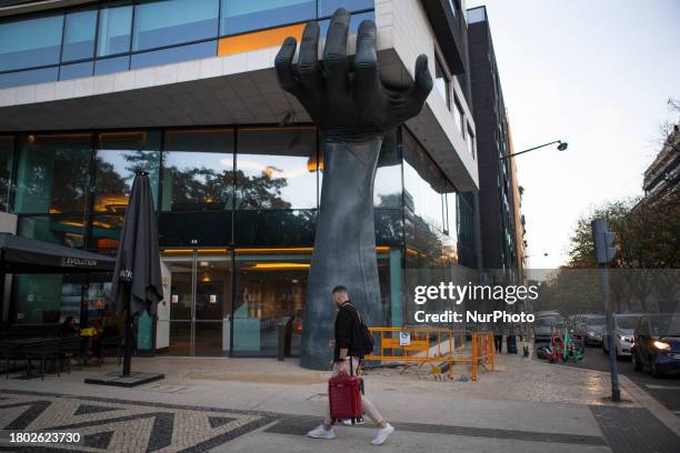 People are walking by a hotel with their suitcases in Lisbon, Portugal, on November 25, 2023. During Black Friday week in Portugal, the economy is...
