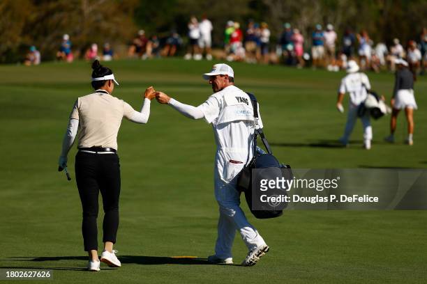 Amy Yang of Korea and caddie Jan Meierling celebrate after Yang holed out from the fairway on the 13th hole during the final round of the CME Group...