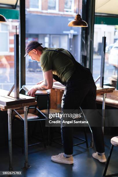 waiter collecting chairs in a cafe - closing time stock pictures, royalty-free photos & images