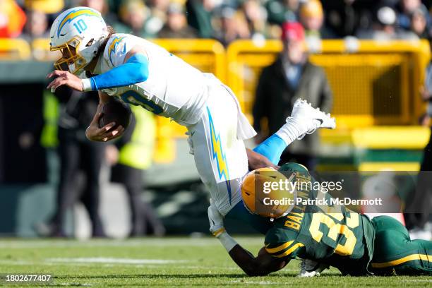 Justin Herbert of the Los Angeles Chargers runs with the ball while being tackled by Corey Ballentine of the Green Bay Packers in the third quarter...