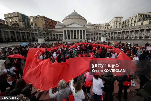 People participating in the flash mob to mark the International Day for the Elimination of Violence against Women, with a long red ribbon, in...