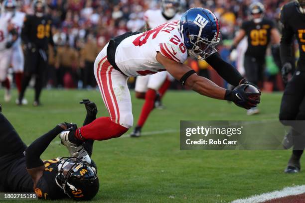 Saquon Barkley of the New York Giants scores a touchdown after a catch while defended by Kamren Curl of the Washington Commanders during the fourth...