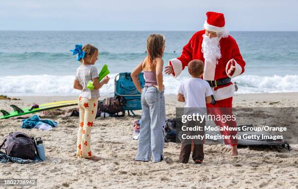 Dana Point, CA Mike Mitrowski, right, of Laguna Niguel talks with young surfing fans on the beach before competing in the 12th annual Surfing Santa...