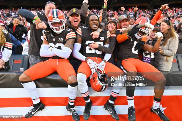Ronnie Hickman, Martin Emerson Jr. #23, and Greg Newsome II of the Cleveland Browns celebrate with fans after beating the Pittsburgh Steelers 13-10...