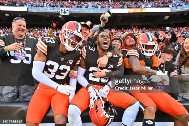 Ronnie Hickman, Martin Emerson Jr. #23, and Greg Newsome II of the Cleveland Browns celebrate with fans after beating the Pittsburgh Steelers 13-10...