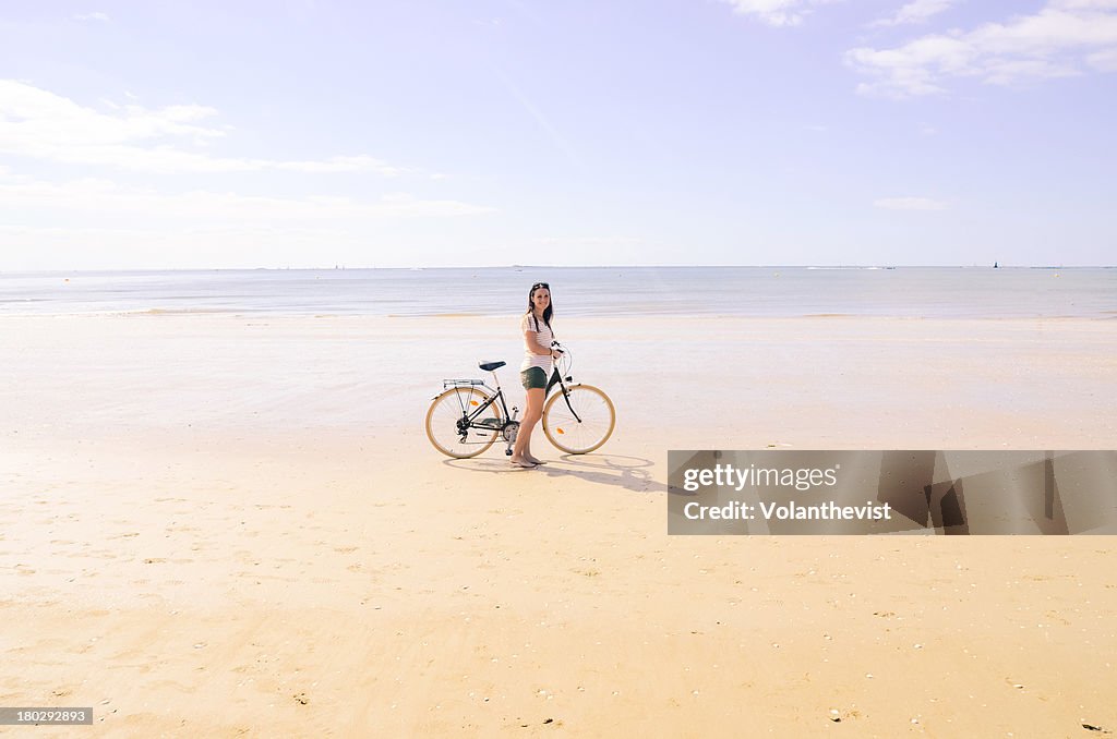 Woman with a bicycle on the beach in summer