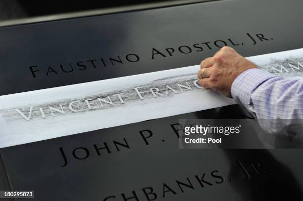 Ron Joy makes a rubbing of his friend's name, New York Fire Department firefighter Capt. Vincent Giammona, at the South reflecting pool of the 9/11...