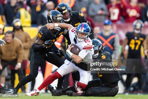 Tommy DeVito of the New York Giants is tackled by Jamin Davis of the Washington Commanders as he runs with the ball during an NFL football game...