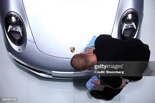 An employee cleans the hood of a Porsche 911 automobile, produced by Porsche SE, at the 65th Frankfurt International Motor Show in Frankfurt,...