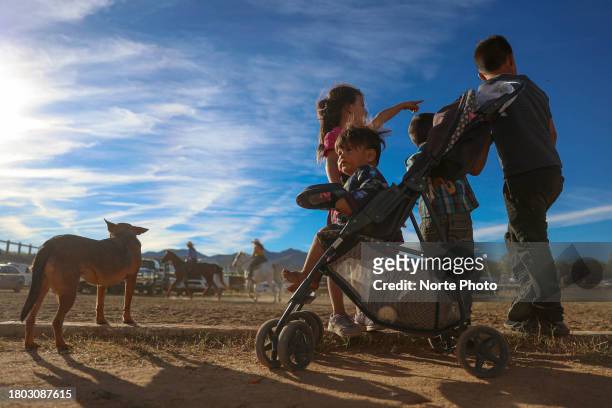 Four children and their dog watch while riders warm up their horses during the third competition date of the Sonora Rodeo circuit on November 19,...