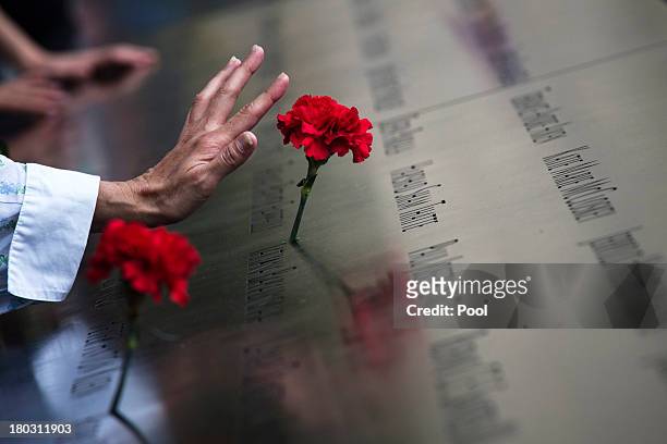 Woman touches a carnation left on a name inscribed into the North Pool during 9/11 Memorial ceremonies marking the 12th anniversary of the 9/11...