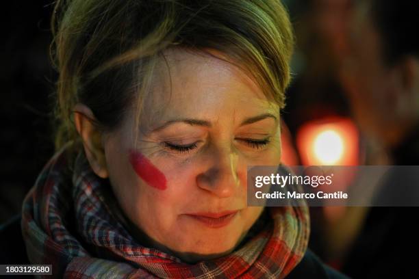 Woman with a red mark on her face, during a torchlight procession for the International Day for the Elimination of Violence against Women. In Italy...