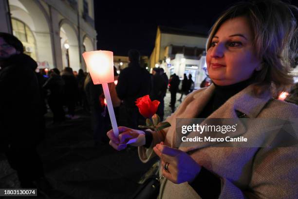 Woman with a flower and a torch during a torchlight procession for the International Day for the Elimination of Violence against Women. In Italy the...