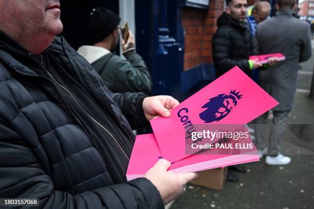 Members of the 1878s, Everton's supporter group, distribute leaflets reading "Corrupt" next to the Premier League logo, to protest over the club...