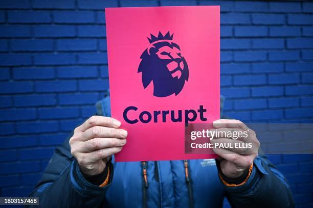 Member of the 1878s, Everton's supporter group, distributes leaflets reading "Corrupt" next to the Premier League logo, to protest over the club...