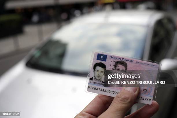 Man holds the first French smart card driver's license in front of a car, on September 11, 2013 in Paris. This secured new driver's license,...