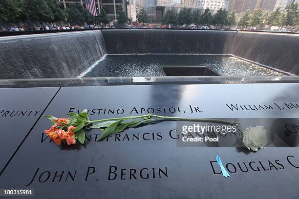 Flowers lay over names at the South Tower pool of the 9/11 Memorial during ceremonies for the twelfth anniversary of the terrorist attacks on lower...