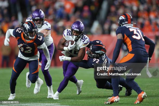 Running back Ty Chandler of the Minnesota Vikings rushes the football past Jonathan Harris and Nik Bonitto of the Denver Broncos during the second...