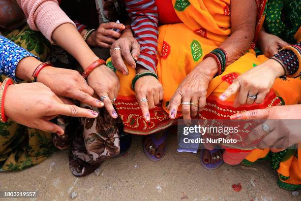 Women in Jaipur, Rajasthan, India, are displaying their fingers marked with indelible ink after casting their votes for the Rajasthan Assembly...