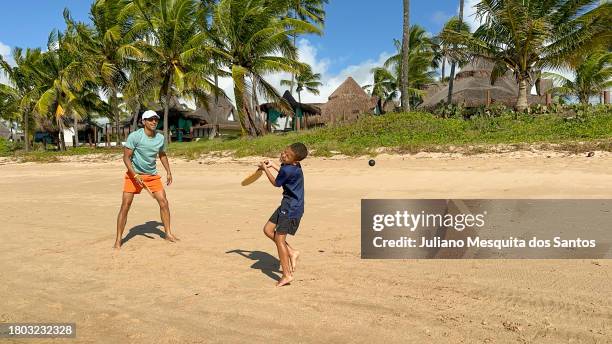 father playing with his son on the beach sand - racketball stock pictures, royalty-free photos & images