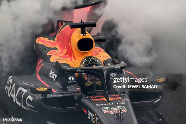 Red Bull Racing's Dutch driver Max Verstappen performs a burnout after winning the Abu Dhabi Formula One Grand Prix at the Yas Marina Circuit in the...