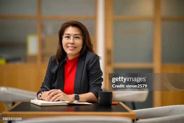 strahlendes selbstbewusstsein: das lächeln einer asiatisch-chinesischen geschäftsfrau in einem kollaborativen arbeitsbereich einfangen - director stock-fotos und bilder