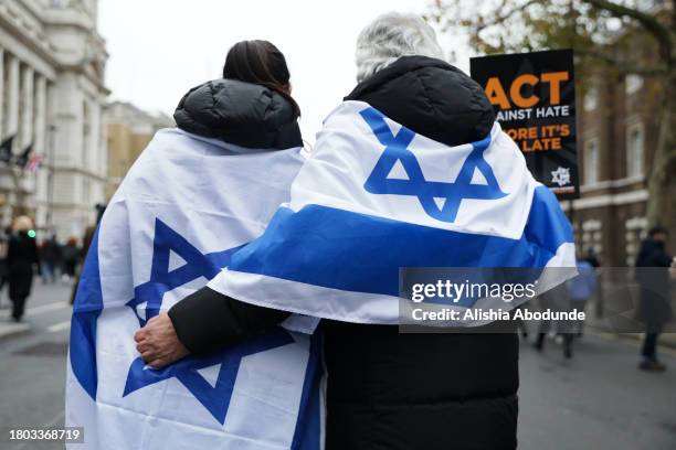 Protestors wear flags of Israel on their backs as they march against anti-Semitism on November 26, 2023 in London, England. The ongoing war between...